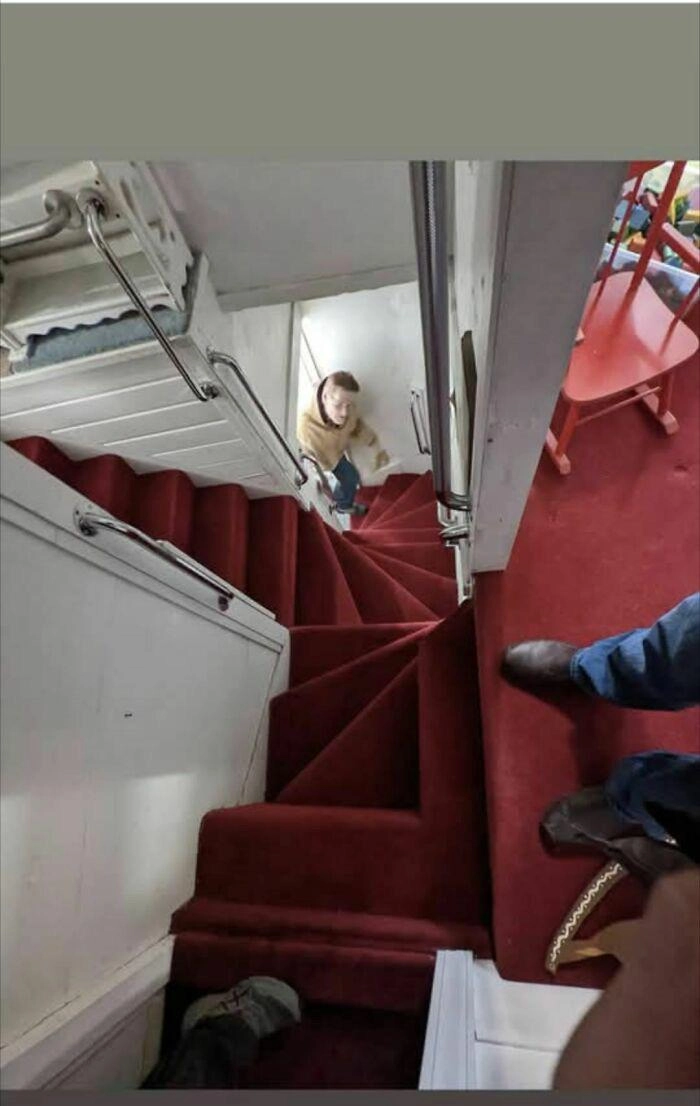 Photo of narrow red stairs leading to different floors in different directions. The way they twist and merge is chaotic and likely to cause accidents on a regular basis.