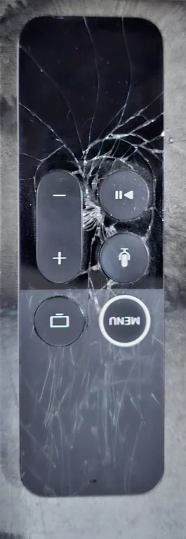 An Apple TV remote with a broken glass surface.
