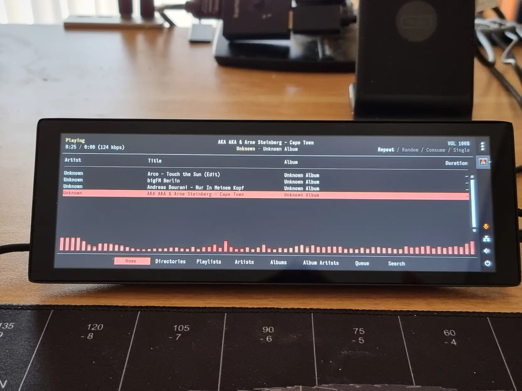 Photo of a small bit wide touch screen on my desk. It shows rmpc, a terminal client for the mpd music server.